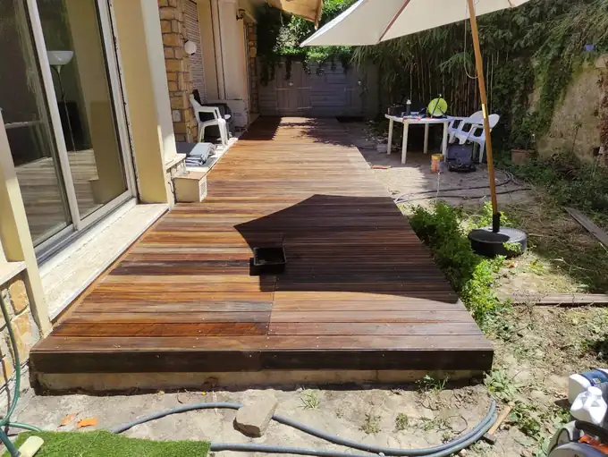 Terrasse en bois en cours d’aménagement devant une maison